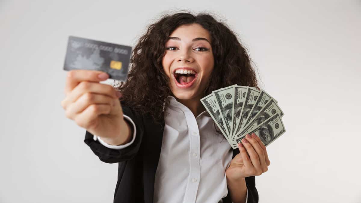 happy woman holding money and credit cards