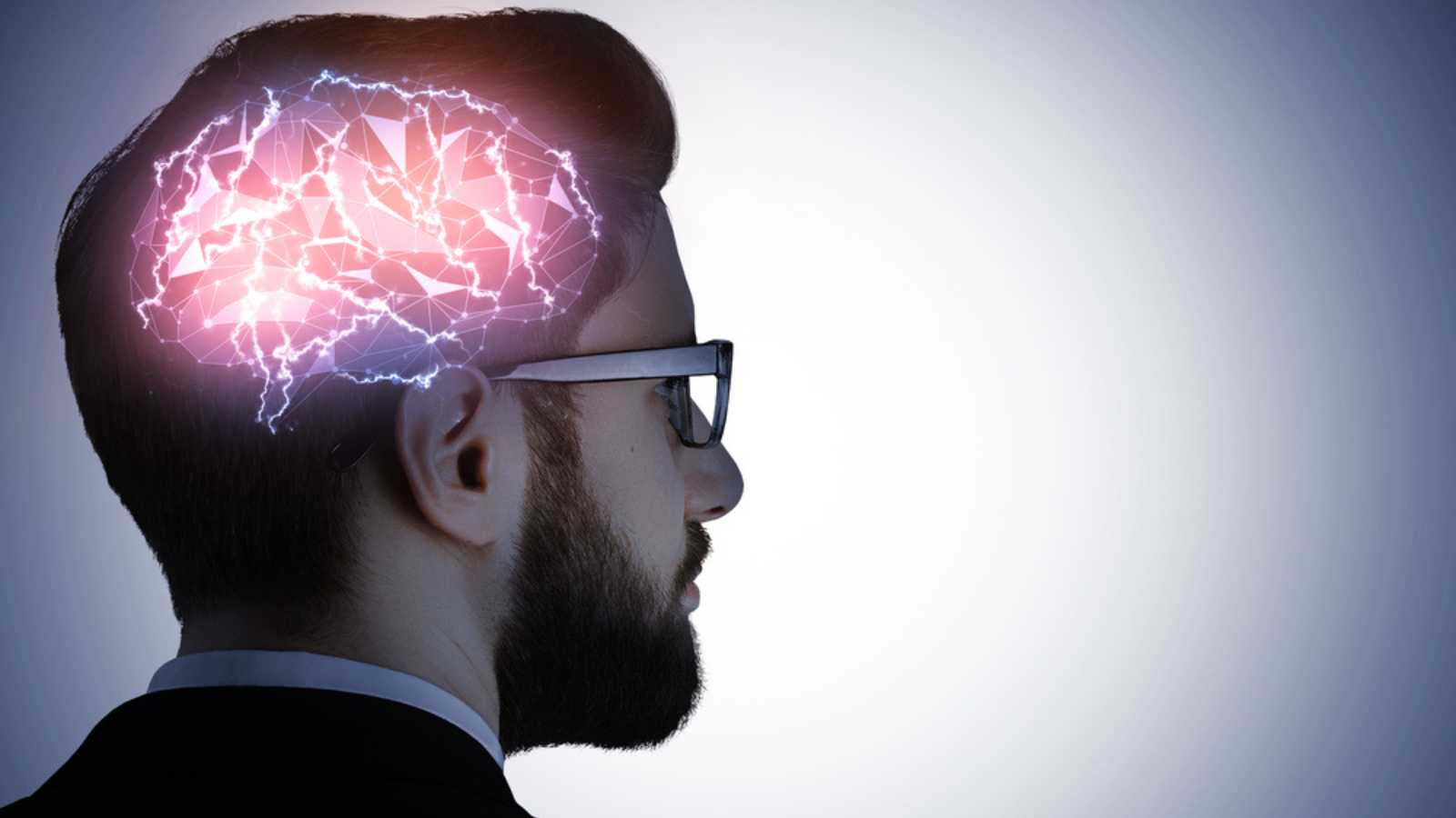Side portrait of handsome caucasian busiessman in glasses with glowing digital brain on gray background. Artificial mind concept
