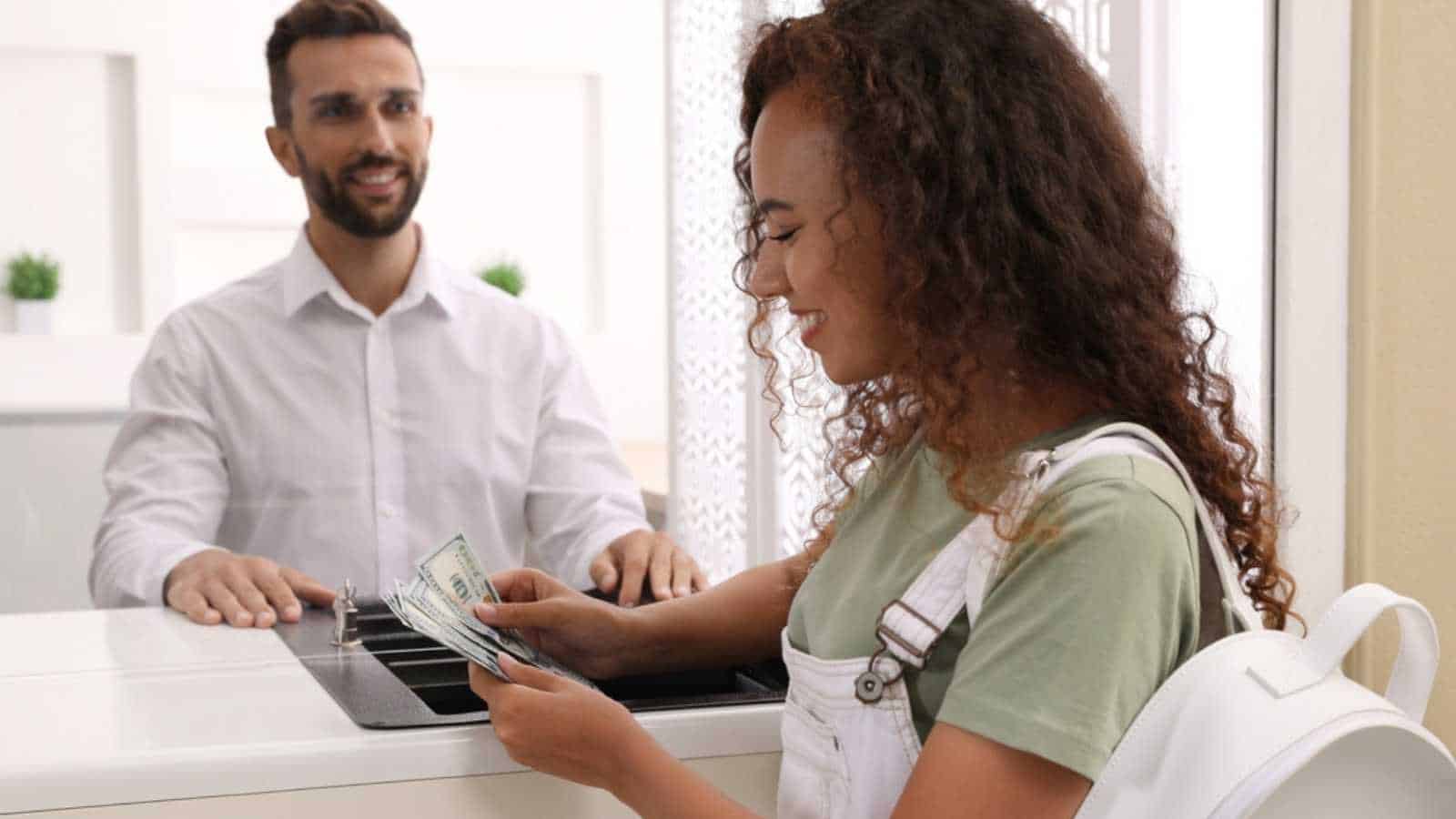 African American woman with money at cash department window in bank. Currency exchange