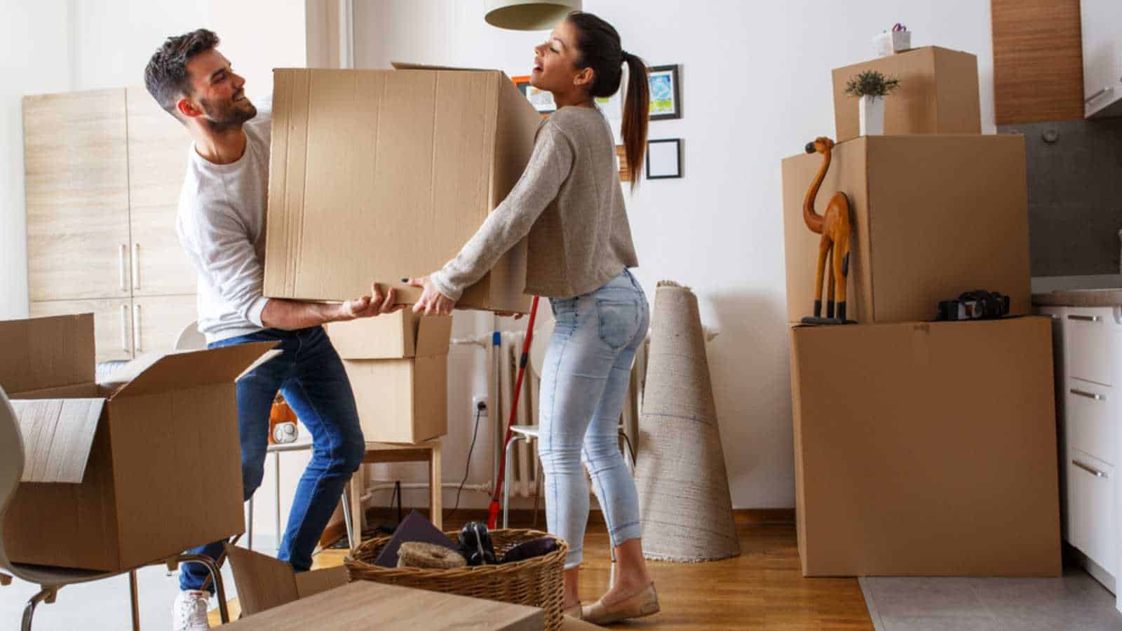 Young couple carrying big cardboard box at new home.Moving house.