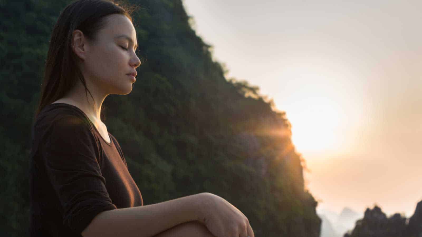 woman relaxing and meditating in nature, during sunset. Peaceful zen.