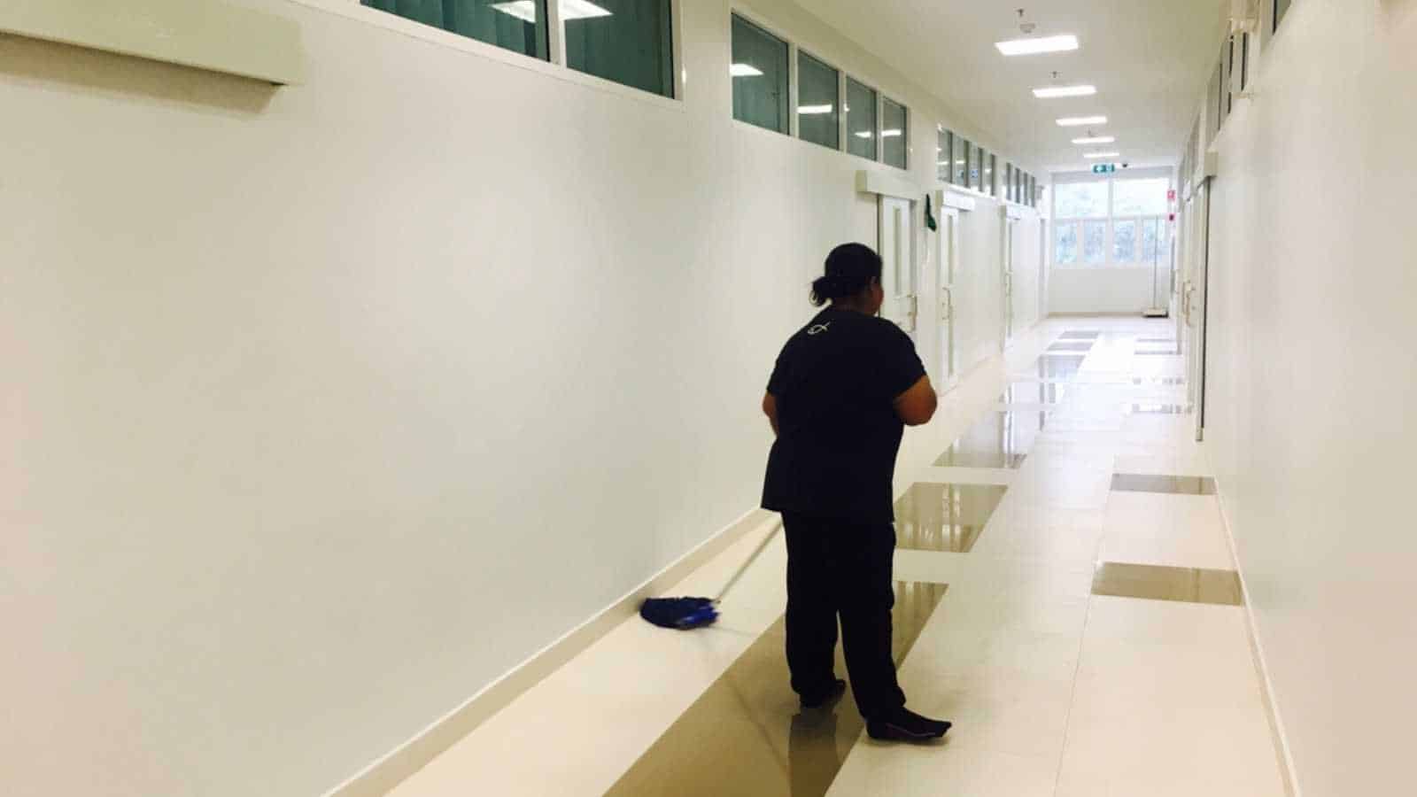Women janitor mopping floor in school hallway classroom. Cleaning services concept.