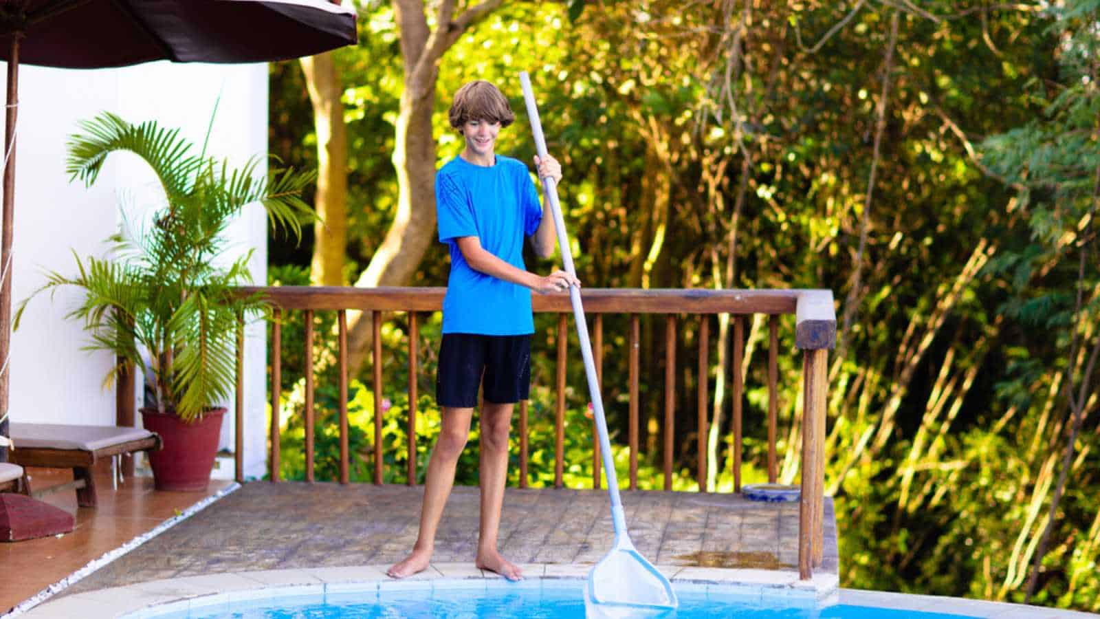 Boy cleaning swimming pool. Maintenance and service for outdoor pool. Teenager after school job and house help. Teen student picking foliage leaf out of water. Garden and backyard chores.