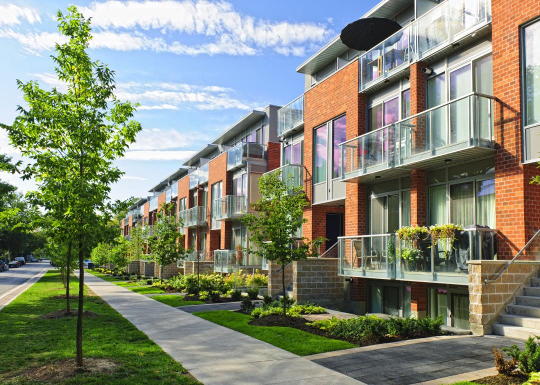 Modern brick and glass townhouses on a tree-lined urban street.
